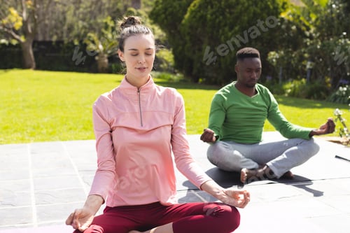 Preview: Diverse couple practicing yoga and meditating in garden