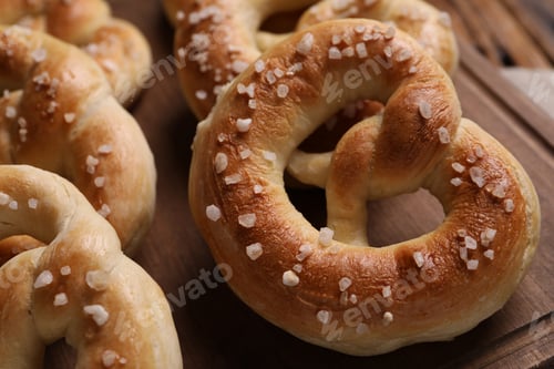 Preview: Tasty salted pretzels on wooden table, closeup