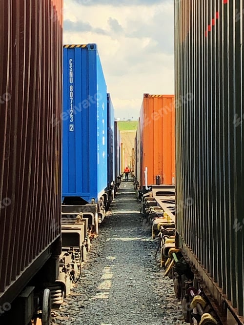 Preview: A port worker inspecting shipping container trains at a busy dock or rail port industrial site