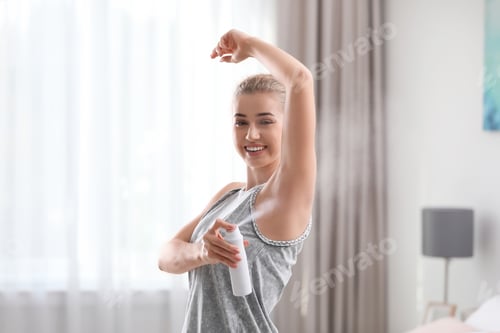 Preview: Beautiful young woman applying deodorant in bedroom
