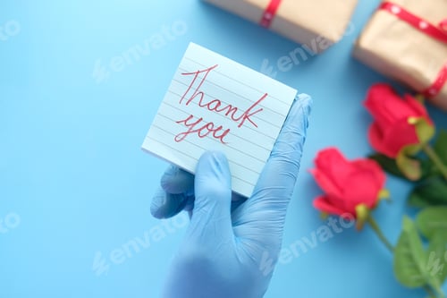 Preview: person hand in latex gloves holding thank you letter