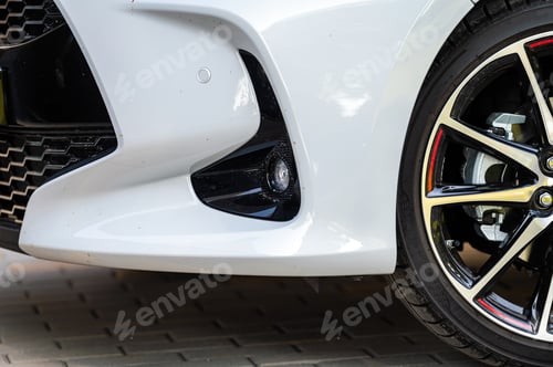 Preview: closeup of the wheels and bumpers of a car parked in the yard of a residential house, lower section