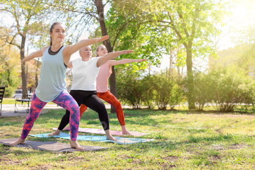 Preview: Group of women practicing yoga in park on sunny day