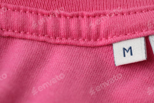 Preview: Clothing label with size on pink garment, above view. Space for text