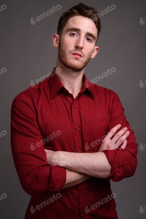 Preview: Young handsome businessman wearing red shirt against gray backgr