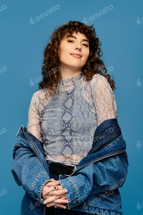 Preview: Stylish young woman showcases fashion against a vibrant blue backdrop in an artistic portrait