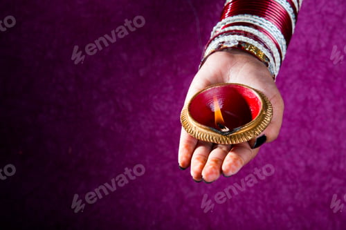 Preview: Female hand holding lit earthen lamp at Diwali festival in India