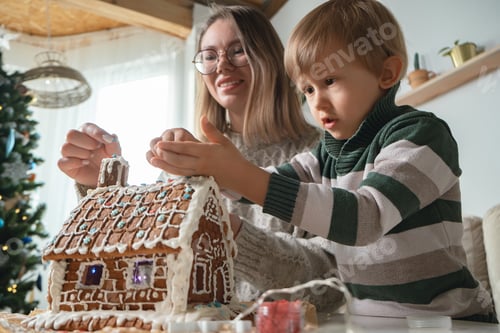 Preview: Little boy with mother decorating christmas gingerbread house together