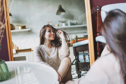 Preview: Beautiful long hair asian girl look at mirror sitting on floor at home