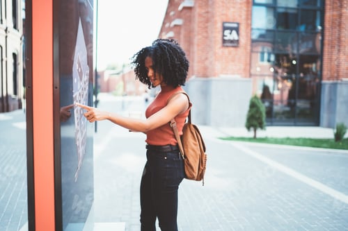 Preview: Black female exploring map on informational board in street