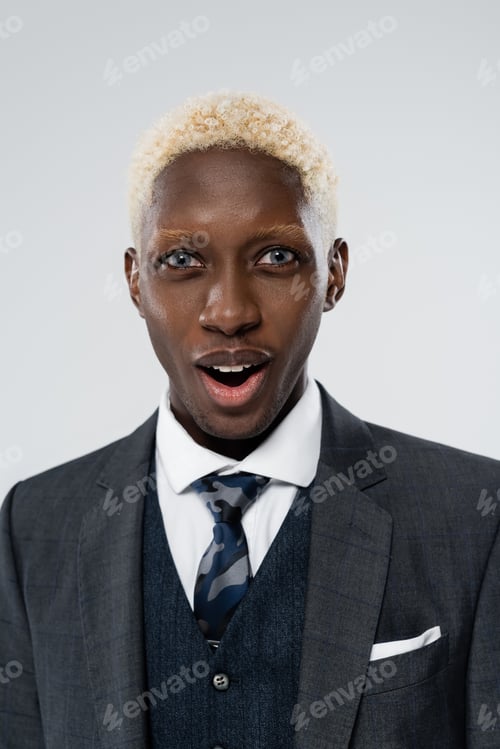 Preview: portrait of blonde and shocked african american man with blue eyes isolated on grey