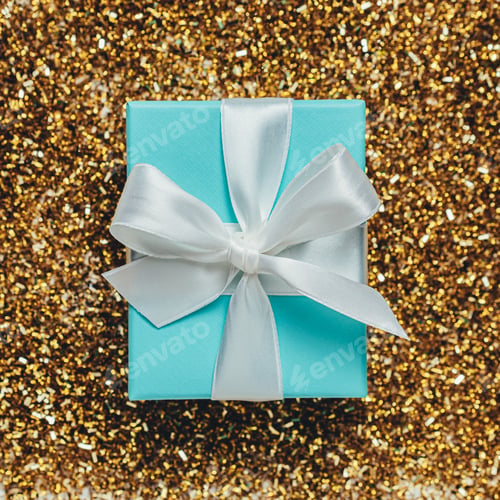 Preview: Beautiful blue gift box tied with silk ribbon on golden sequins and glitter background. Birthday