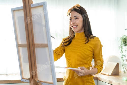 Preview: Asian young talented woman artist coloring on painting board in house.