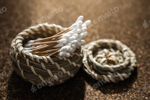 Preview: Wooden Cotton Swabs in Woven Basket on Cork Surface