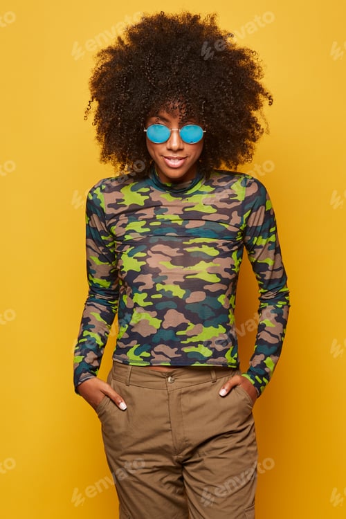 Preview: Trendy ethnic lady in sunglasses on bright backdrop