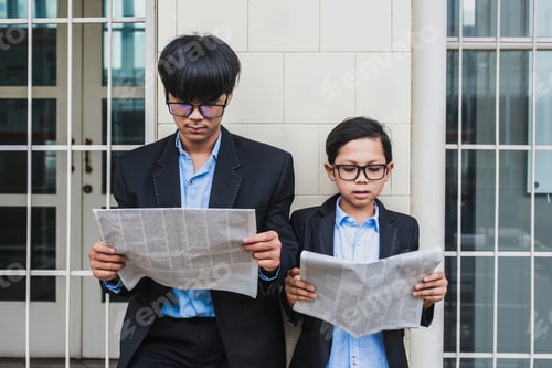 Preview: Two asian brothers in office looks reading newspaper