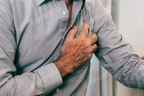 Preview: Senior man holding hand on chest and suffering from heart problem at home