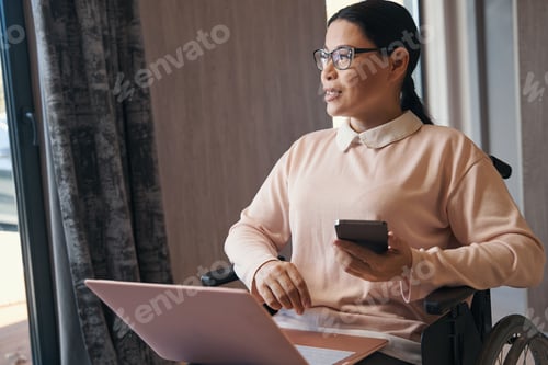 Preview: Serene mature woman with disability using gadgets indoors