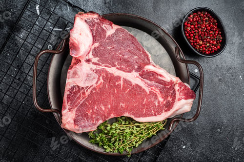 Preview: Fresh raw T-bone marbled beef meat Steak on a steel tray. Black background. Top view