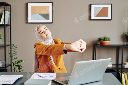 Preview: Young tired female office worker keeping her stretched arms in front of herself