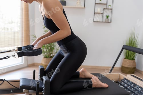 Preview: Young woman exercising on pilates reformer bed