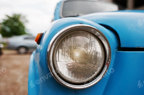 Preview: Old vintage car headlight close up at blue car.