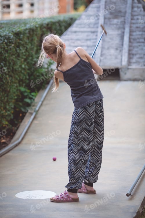 Preview: Happy little girl playing mini golf.