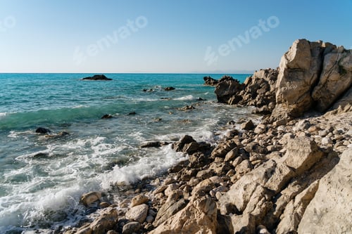 Preview: Rocky shore with crystal clear waters under blue sky