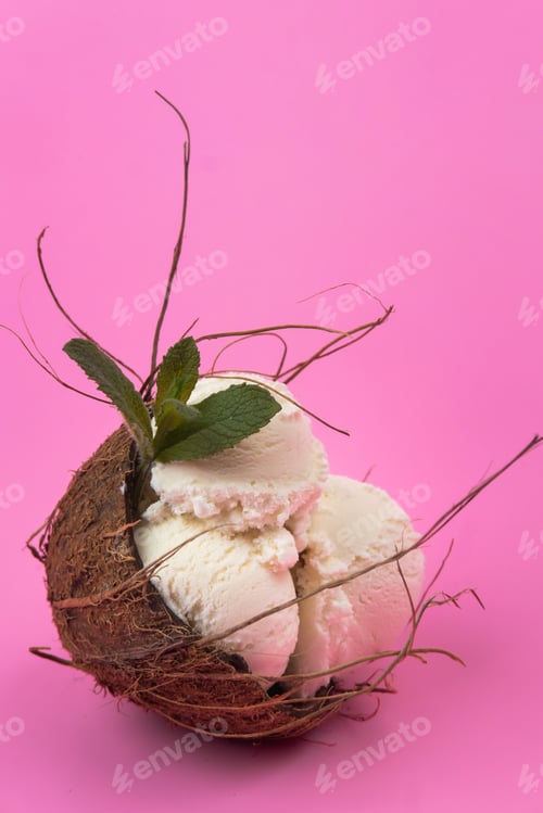 Preview: Vanilla ice cream balls in an empty coconut decorated with mint leaves on a pink background