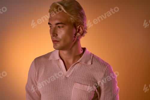 Preview: Handsome young man showcases stylish outfit against warm gradient backdrop during photo session