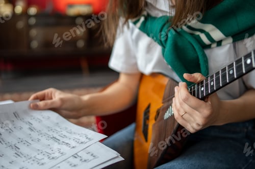 Preview: Female music student examines balalaika notes and chords, planning practice session at home or class