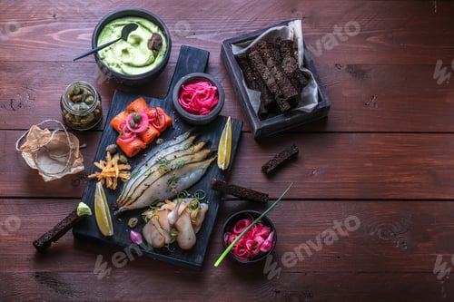 Preview: Assorted marinated fish on dark cutting board, copy space