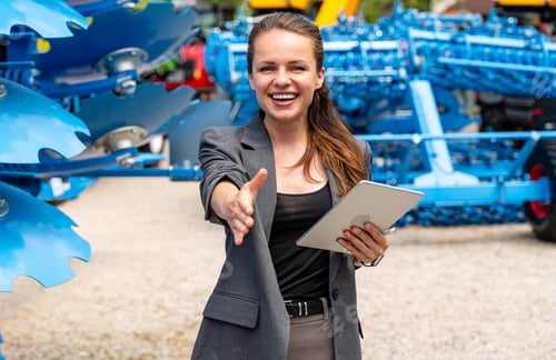 Preview: Professional woman welcoming business collaboration near farm implements