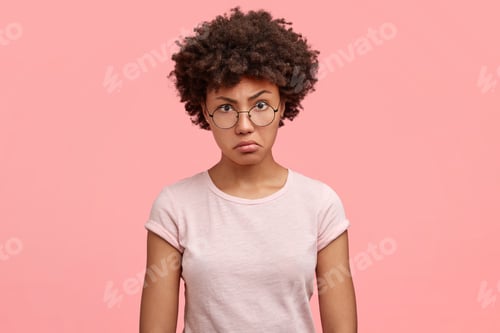 Vista previa: Waist up portrait of dissatisfied African American female with negative angry facial expression, loo