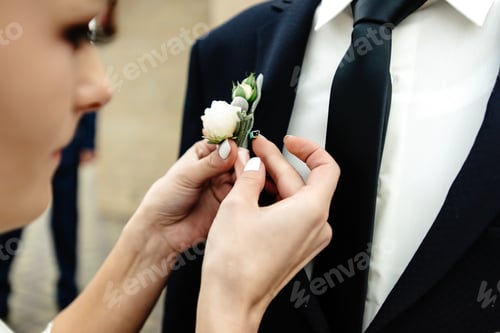Preview: stylish gorgeous bride putting on boutonniere on elegant groom at church ceremony