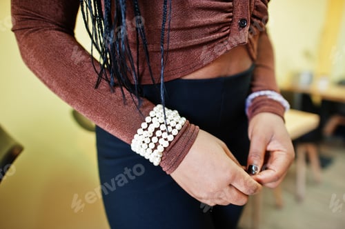 Preview: Hands of african american woman with bracelet chain attached on women's wrist.