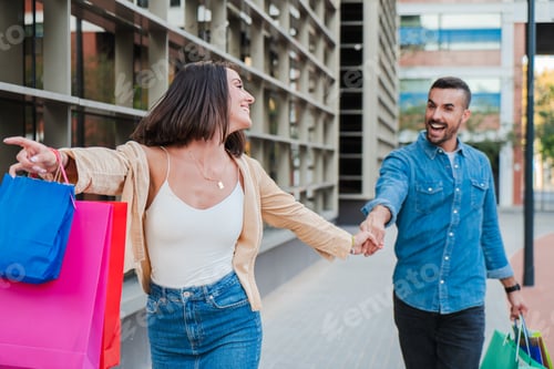 Preview: Young adult customer couple running to mall store carrying shopping bags to buy a sale on a store