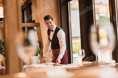 Preview: Smiling waiter serving tables at the restaurant