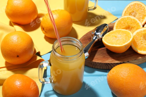 Preview: Freshly squeezed orange juice, fruits and juicer on blue wooden table, closeup