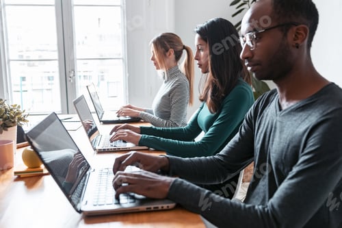 Preview: Line of concentrated employees working with laptops on coworking place.