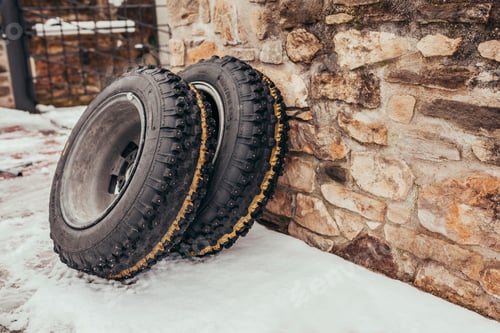 Preview: Studded tyres leaning on a brick wall at snowy winter