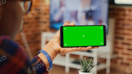 Preview: Young adult looking at horizontal greenscreen on telephone