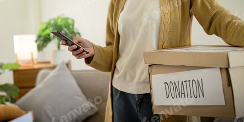Preview: Donation concept. Woman asian holding a donate box with full of clothes. Woman holding clothes