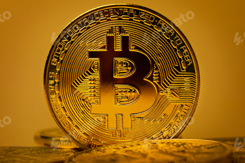 Preview: Closeup of shiny gold bitcoin on yellow backgound