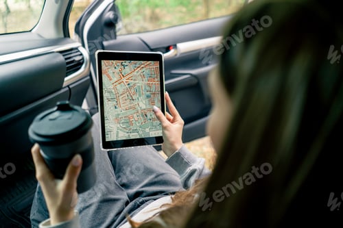 Preview: A girl sits in a car in the front passenger seat and plots a route through the forest using a map