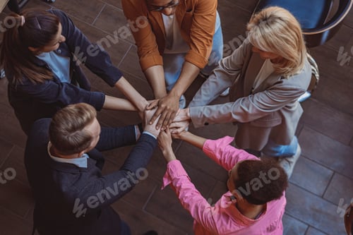 Preview: Top view of colleagues putting their arms in centre standing at office. Community concept