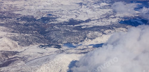 Preview: Snowy mountains background and white clouds above them. Aerial photo from plane's window.
