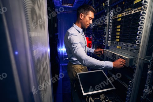 Preview: Experienced male engineer working in server room