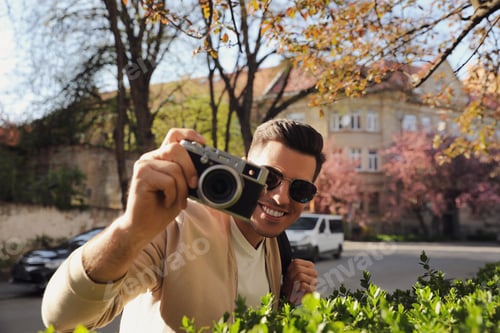 Preview: Happy male tourist with camera on city street
