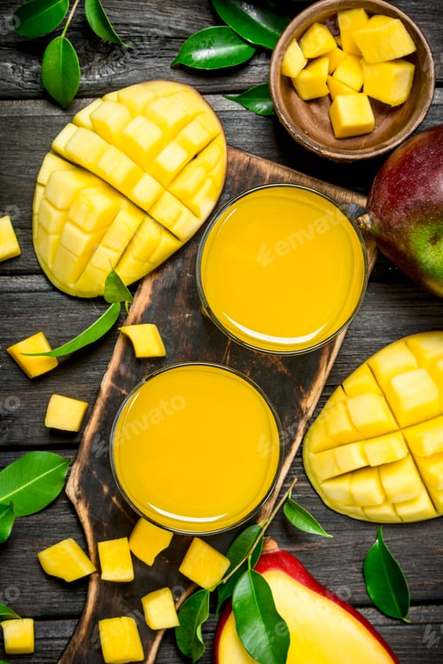 Preview: Mango juice and slices of fresh mango on the cutting Board.